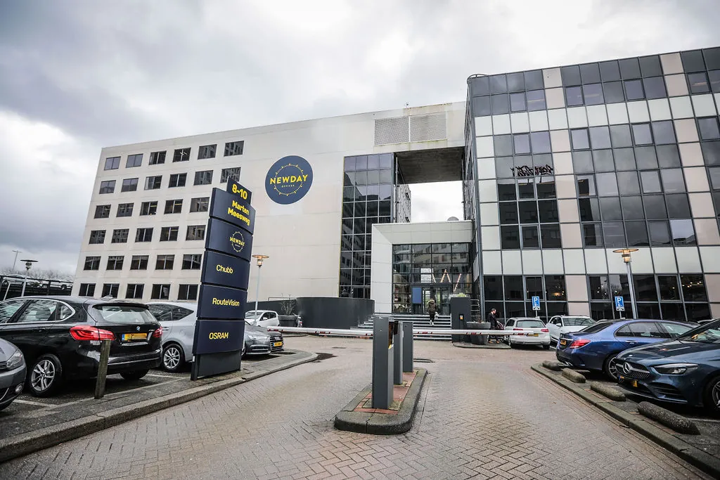 Kantoorgebouw aan de Marten Meesweg 8-10 met parkeergelegenheid en zicht op bedrijfsnamen zoals Newday, Chubb en OSRAM.